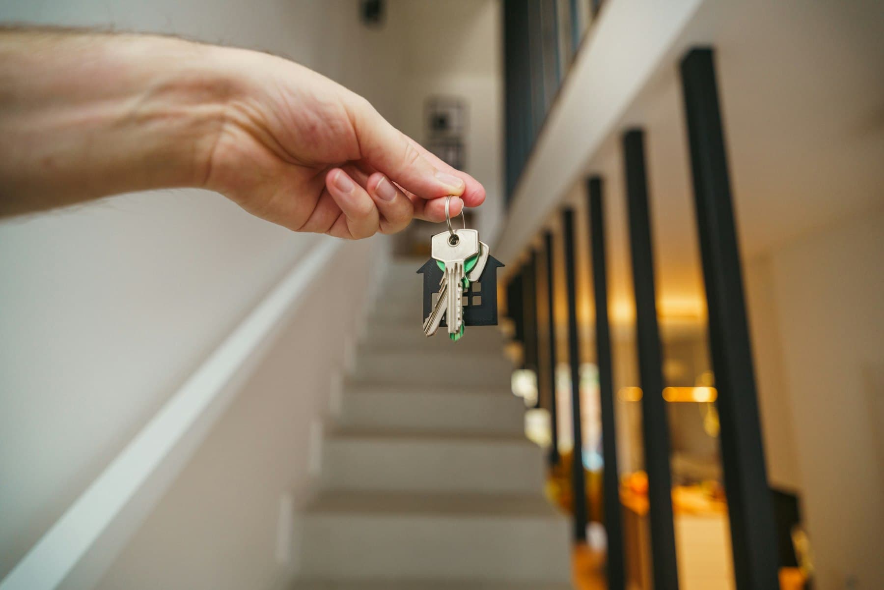 Une main tend un trousseau de clés dans la cage d'escalier d'un appartement